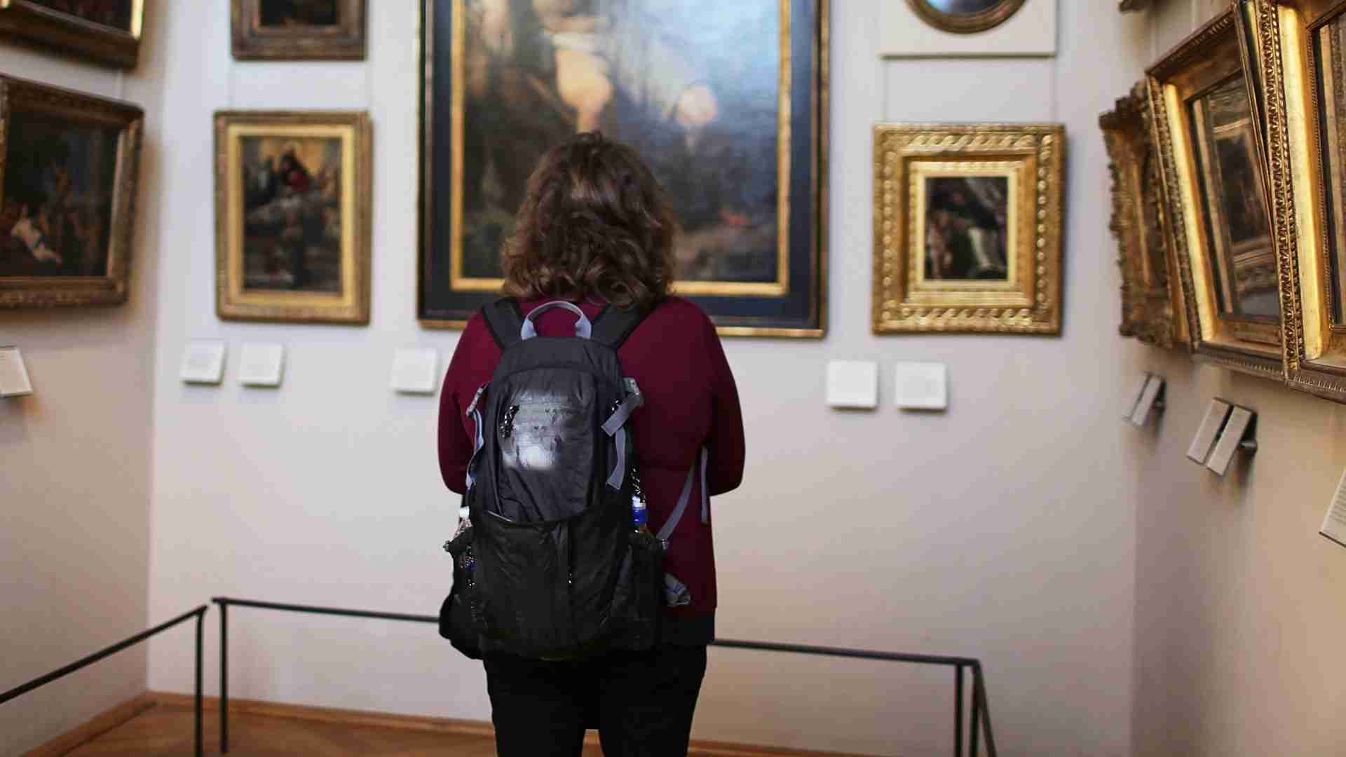 Immagine di donna all'interno di un museo mentre osserva alcuni quadri